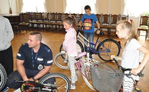 Dzieci z rowerami i policjant