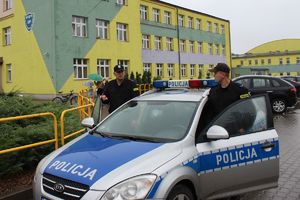 policjanci przy radiowozie przed szkołą