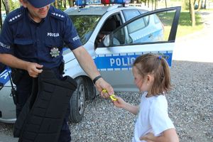 policjant wręcza dziewczynce odblask