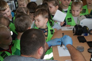 technik pokazuje dzieciom narzędzia służące do zabezpieczenia śladów kryminalistycznych
