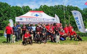 ratownicy WOPR z psami, policjanci i strażak na tle namiotu WOPR