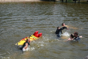 w wodzie chłopak i 3 ratowników. Płyną z noszami