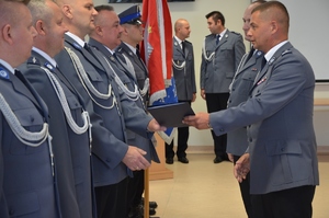 policjanci stoją w rzędzie. Komendant KWP w Bydgoszczy wręcza im akty mianowania na wyższe stopnie służbowe
