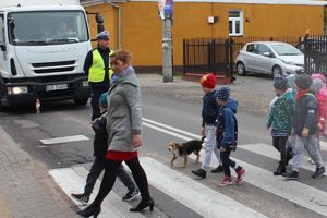 dzieci  w asyście policjantów przechodzą przez jezdnię