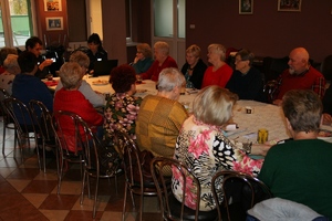 osoby starsze siedzą w sali przy stole