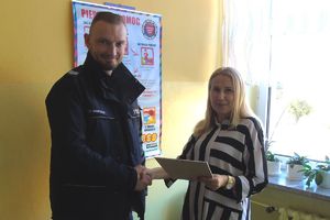 policjant z posterunku przekazuje dar na zbiórkę dla Alanka