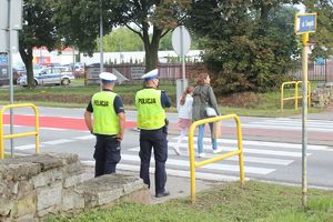 policjanci przy przejściu dla pieszych, na pasach mama z dzieckiem