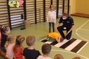 dziecko pokazuje pozycje żółwia, policjantka udziela instruktarzu
